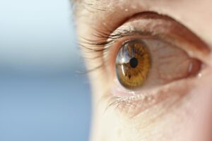 Close-up de olho humano em luz natural, demonstrando a importância da retina e da proteção para garantir os benefícios da luz natural para a sua visão.